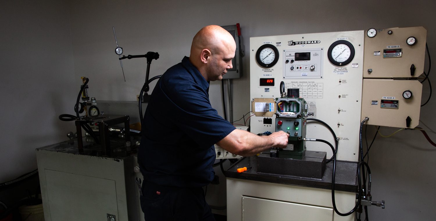 Drake Controls technician function-testing a governor on a Woodward governor test stand
